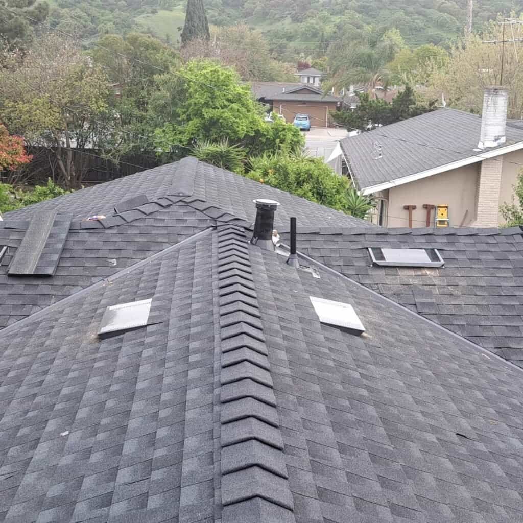 New asphalt shingle roof installation on a house with multiple skylights.