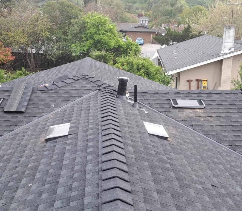 New asphalt shingle roof installation on a house with multiple skylights.
